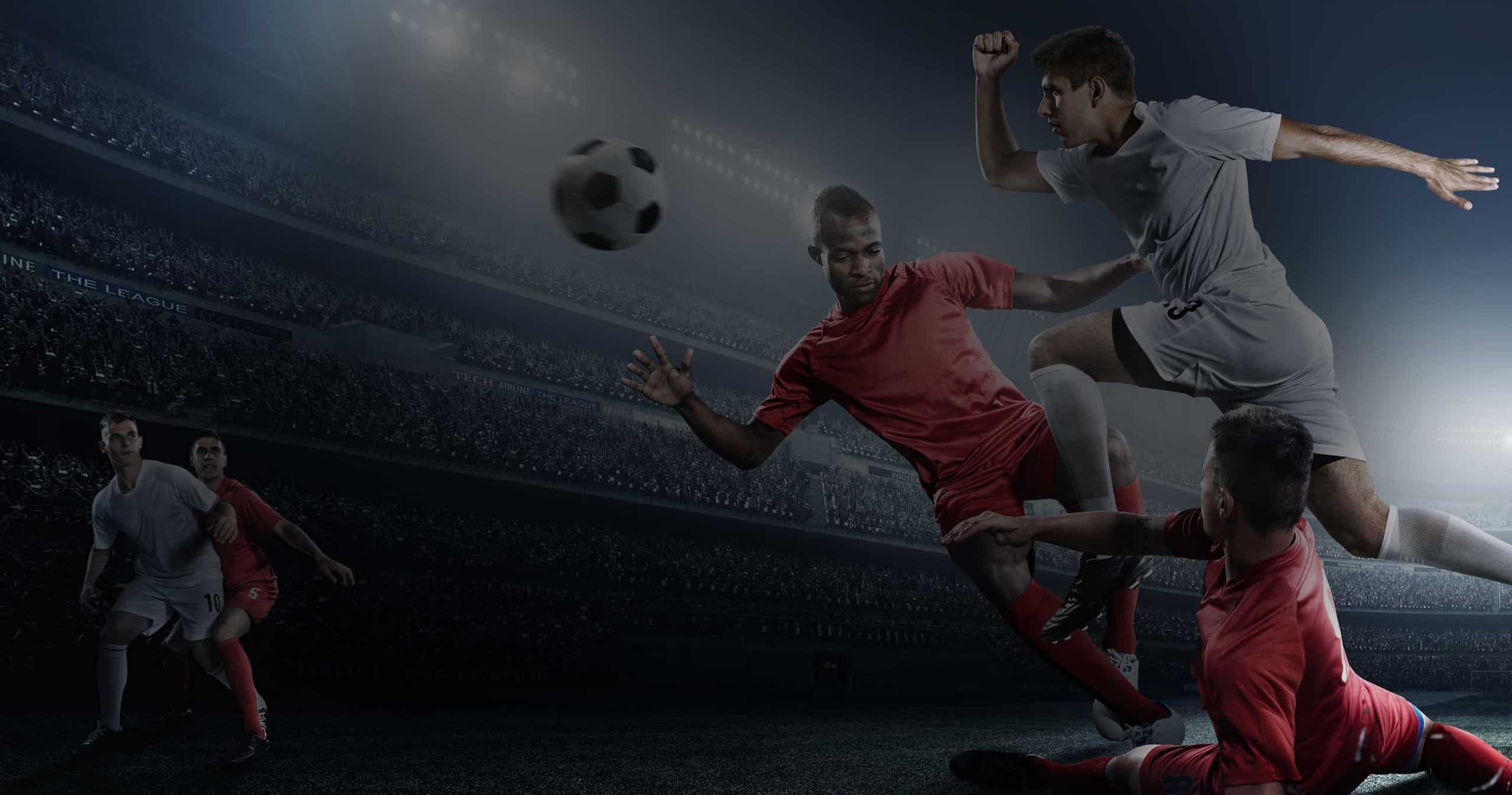 Four soccer players, two in white uniforms and two in red, are actively competing for the ball during a night match in a floodlit stadium. The players display dynamic movements, with one in a white uniform leaping while the others engage near the ground, reminiscent of inflammation in the body responding to stimuli.